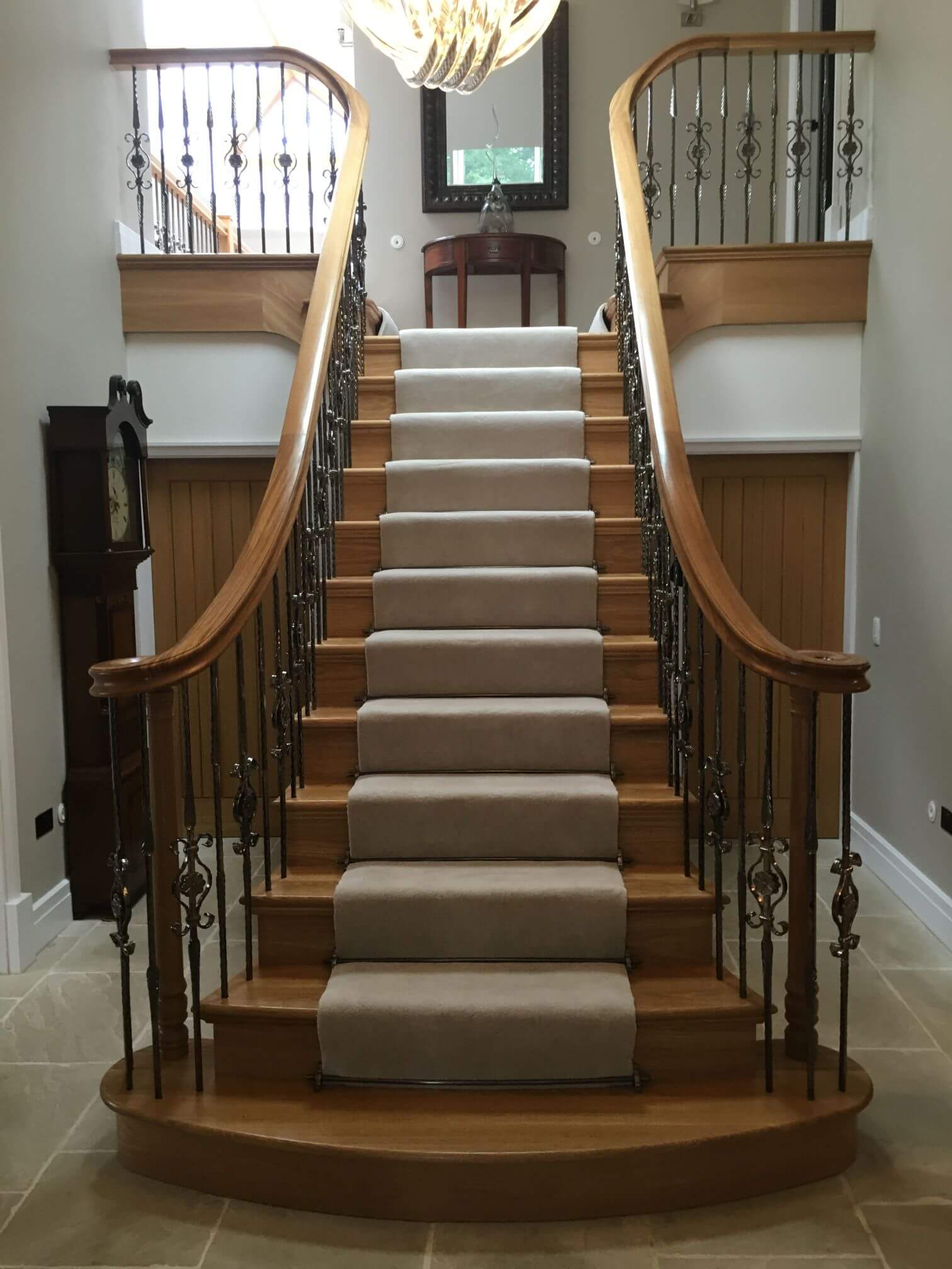 Oak cut string staircase, ornamental metal balustrade, continuous oak handrail