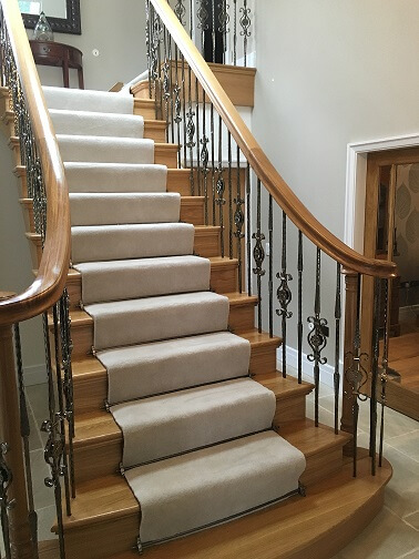 Oak cut string staircase, ornamental metal balustrade, continuous oak handrail