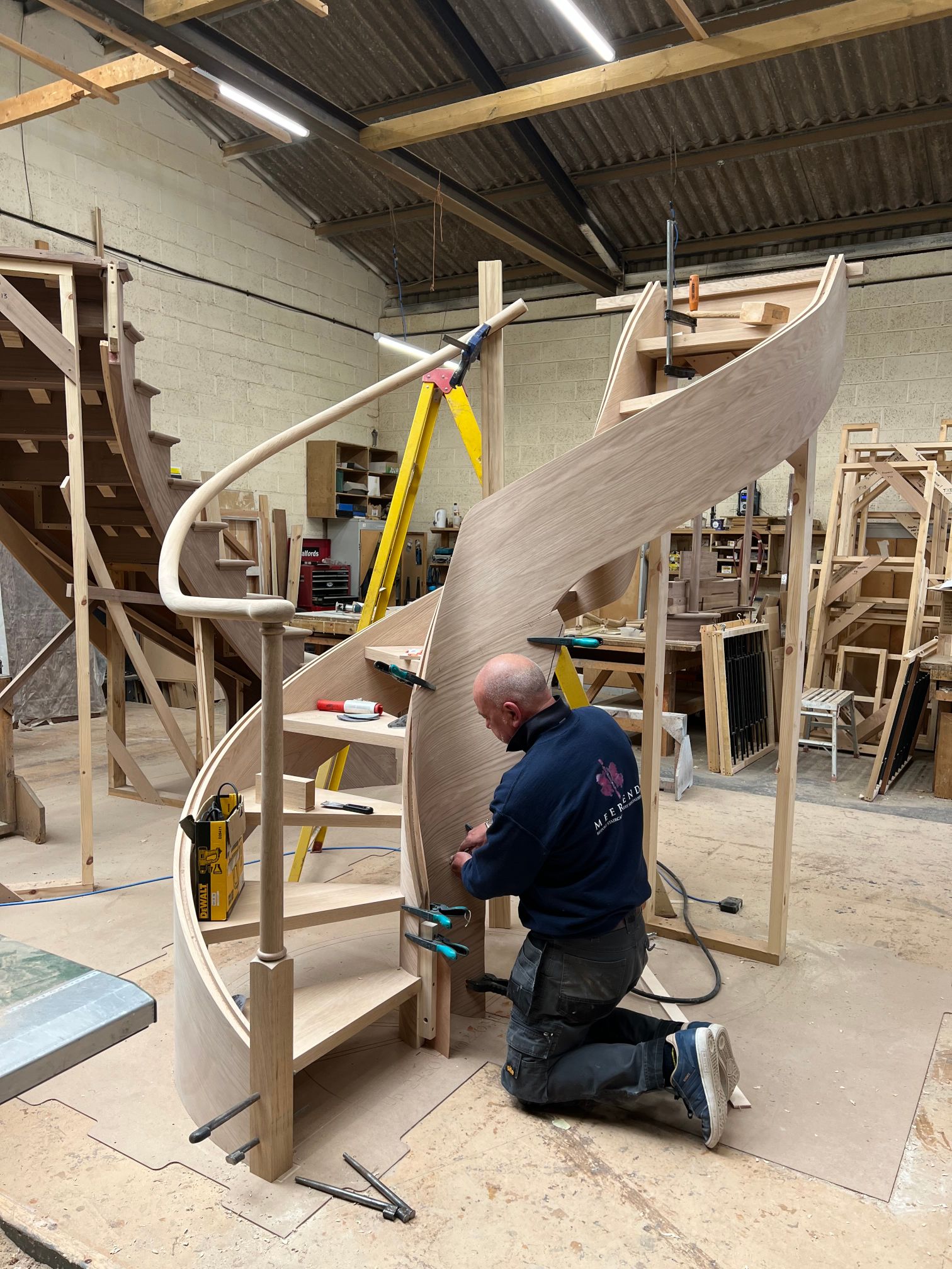 Oak fully helical closed string stair with continuous oak handrail, plain metal bar balustrade.