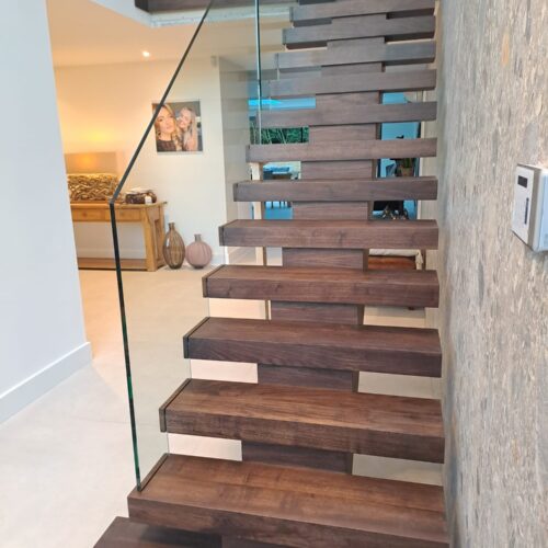 Walnut carriage beam staircase with glass balustrade being fitted
