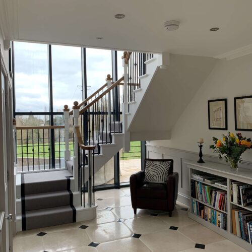 Painted cut string staircase, fabricated metal balustrade, oak handrail & newel caps